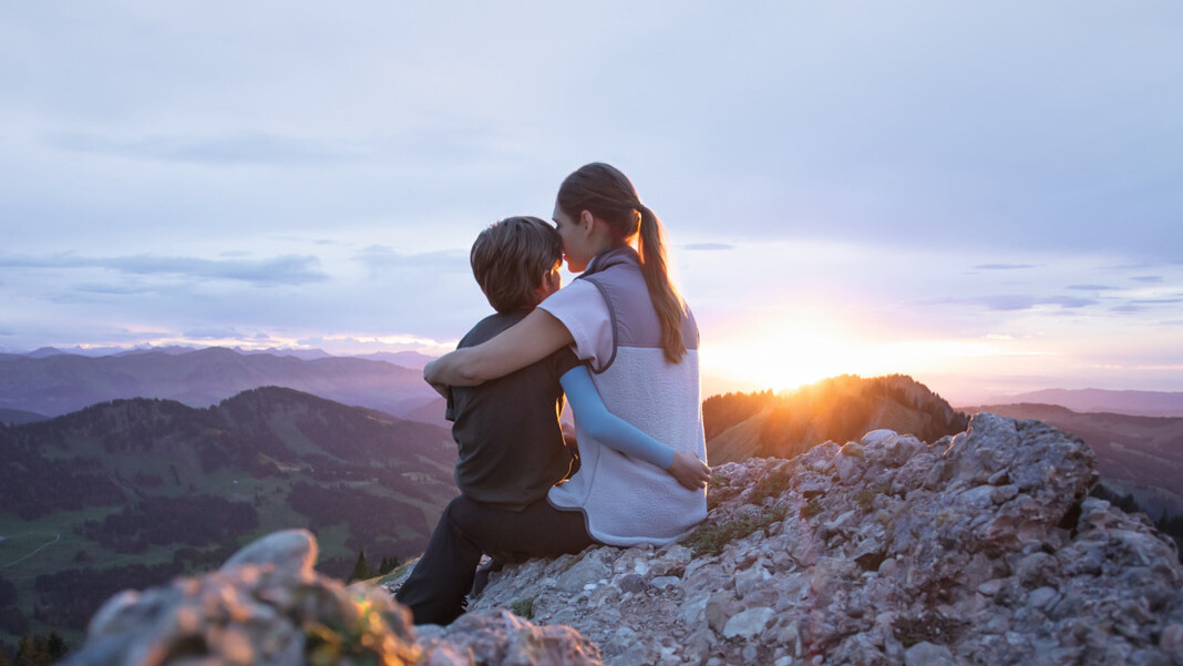 Una madre è seduta con il suo bambino sulla cima di una montagna. Il bambino indossa una manica a compressione. Una madre è seduta con il suo bambino sulla cima di una montagna. Il bambino indossa una manica a compressione.