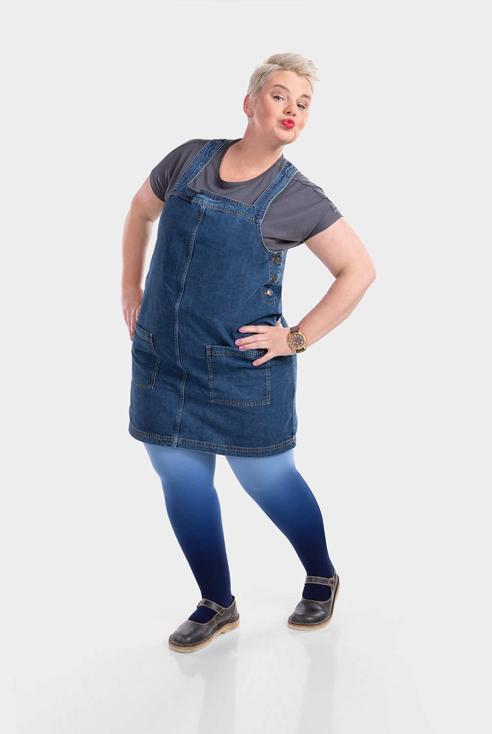 Eine Frau trägt ein Jeans-Latzkleid und dazu eine Kompressionsversorgung in Dip Dye Blau Eine Frau trägt ein Jeans-Latzkleid und dazu eine Kompressionsversorgung in Dip Dye Blau