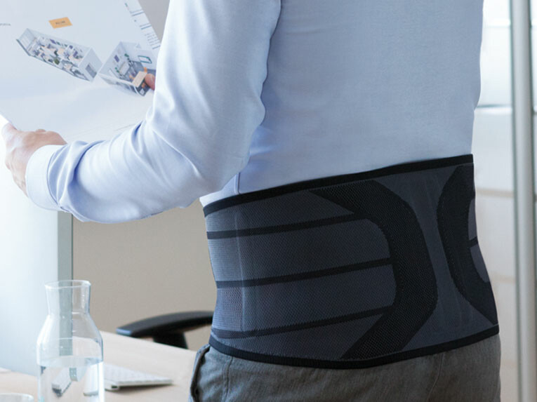 Ein Mann trägt im Büro eine Rückenorthese