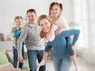 Foto einer Familie im Wohnzimmer auf dem die Frau eine blaue Thoraxbandage trägt