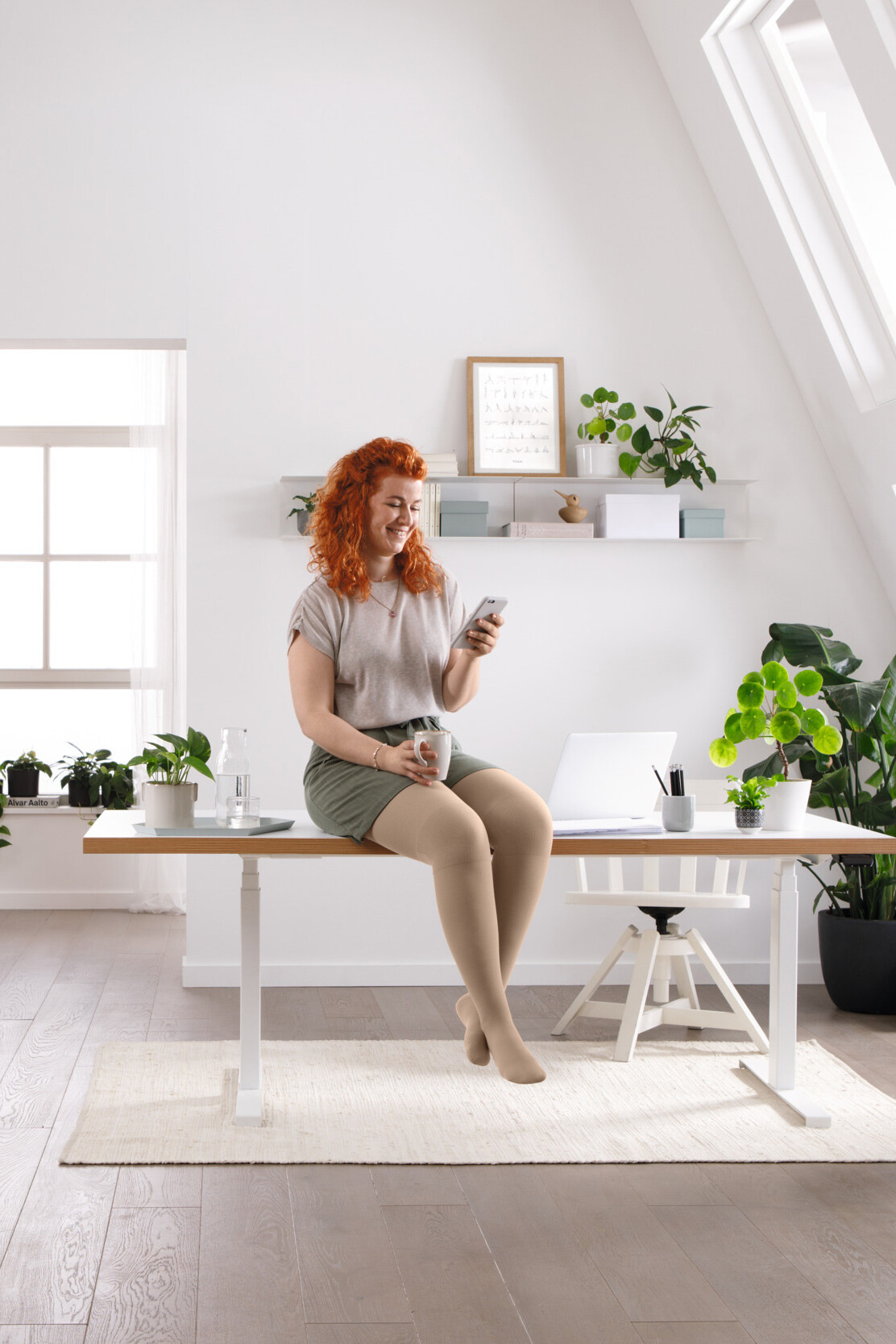 Uma mulher está sentada à secretária e a ler algo no telemóvel Uma mulher está sentada à secretária e a ler algo no telemóvel