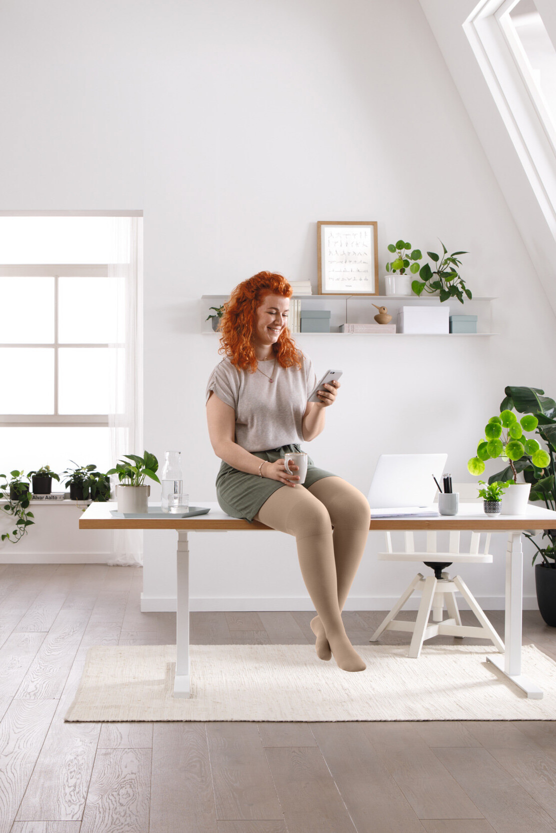 Een vrouw zit aan haar bureau en leest iets op haar mobiele telefoon Een vrouw zit aan haar bureau en leest iets op haar mobiele telefoon