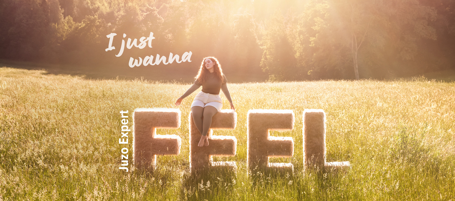 NEU: Juzo Expert Feel Eine Frau sitzt auf den Buchstaben "Feel", im Hintergrund sieht man eine schöne Landschaft