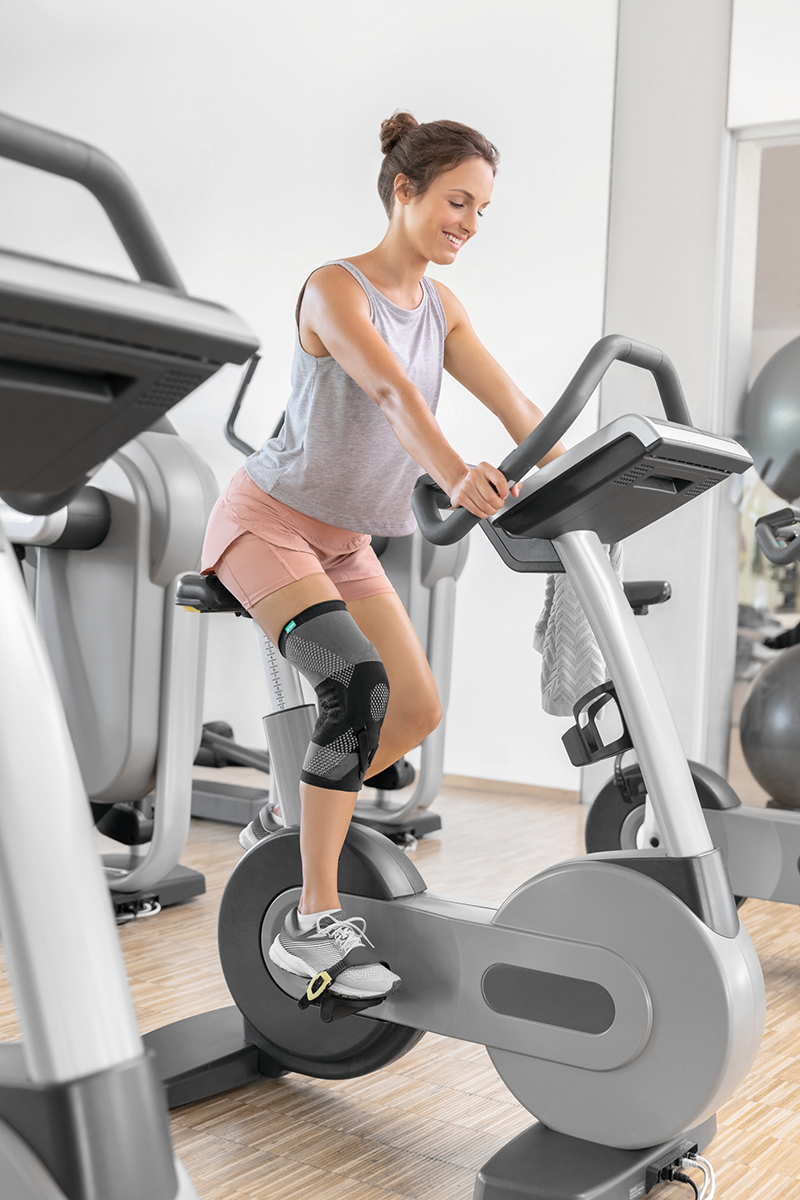 Kvinde i et fitnesscenter med en knæortoser