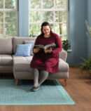 Lifestyle Image Juzo Sensation Fit Woman sitting on her couch, smiling and reading a magazine