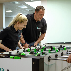 Eine Mitarbeiterin und ein Mitarbeiter spielen in ihrer Pause Kicker
