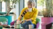 A woman sits in a café. She is drinking a coffee and wearing an orthosis on her wrist.