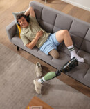 En ung mand ligger på en sofa. Hans benprotese ligger ved siden af ham, og han har en Juzo Classic Seamless-strømpe på.
