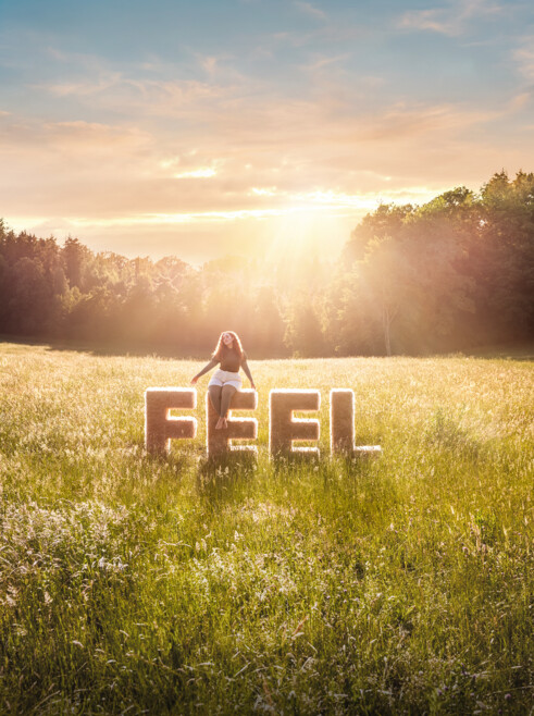 Eine Frau sitzt auf den Buchstaben "Feel" und trägt den Juzo Expert Feel